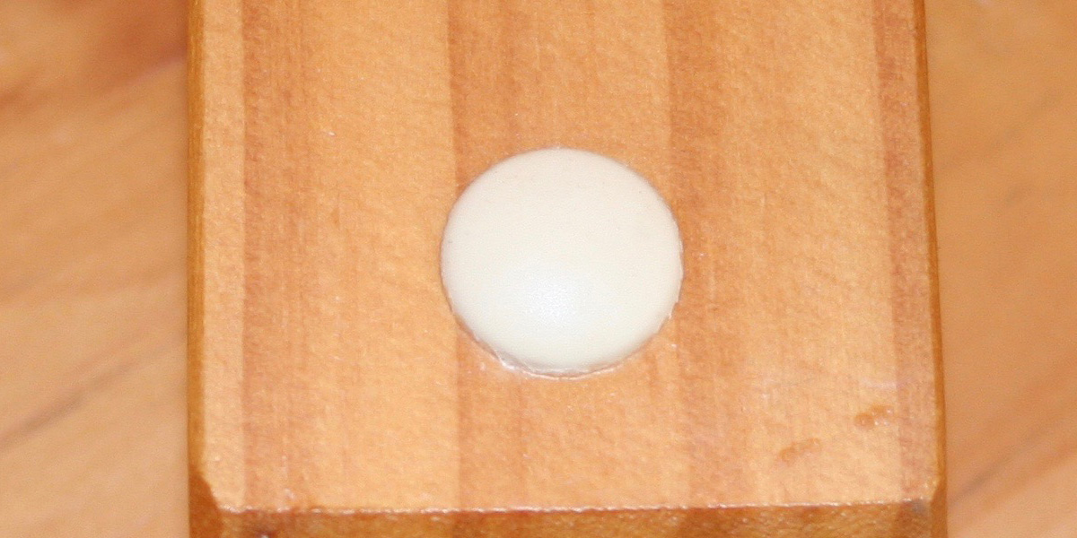 plastic button contrasting with darkened wood